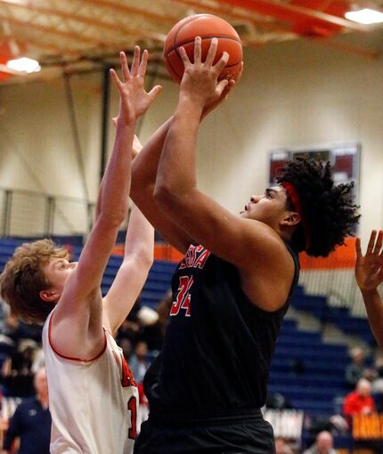 Melissa High School post Trevor Goosby (34) shoots as McKinney North post Kael Nylander (15)...