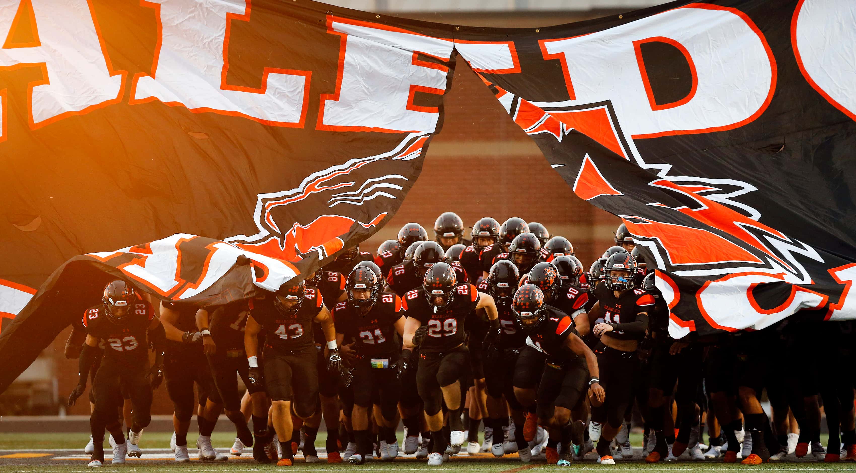 The Aledo Bearcats football team bust through the banner as they take the field to face...