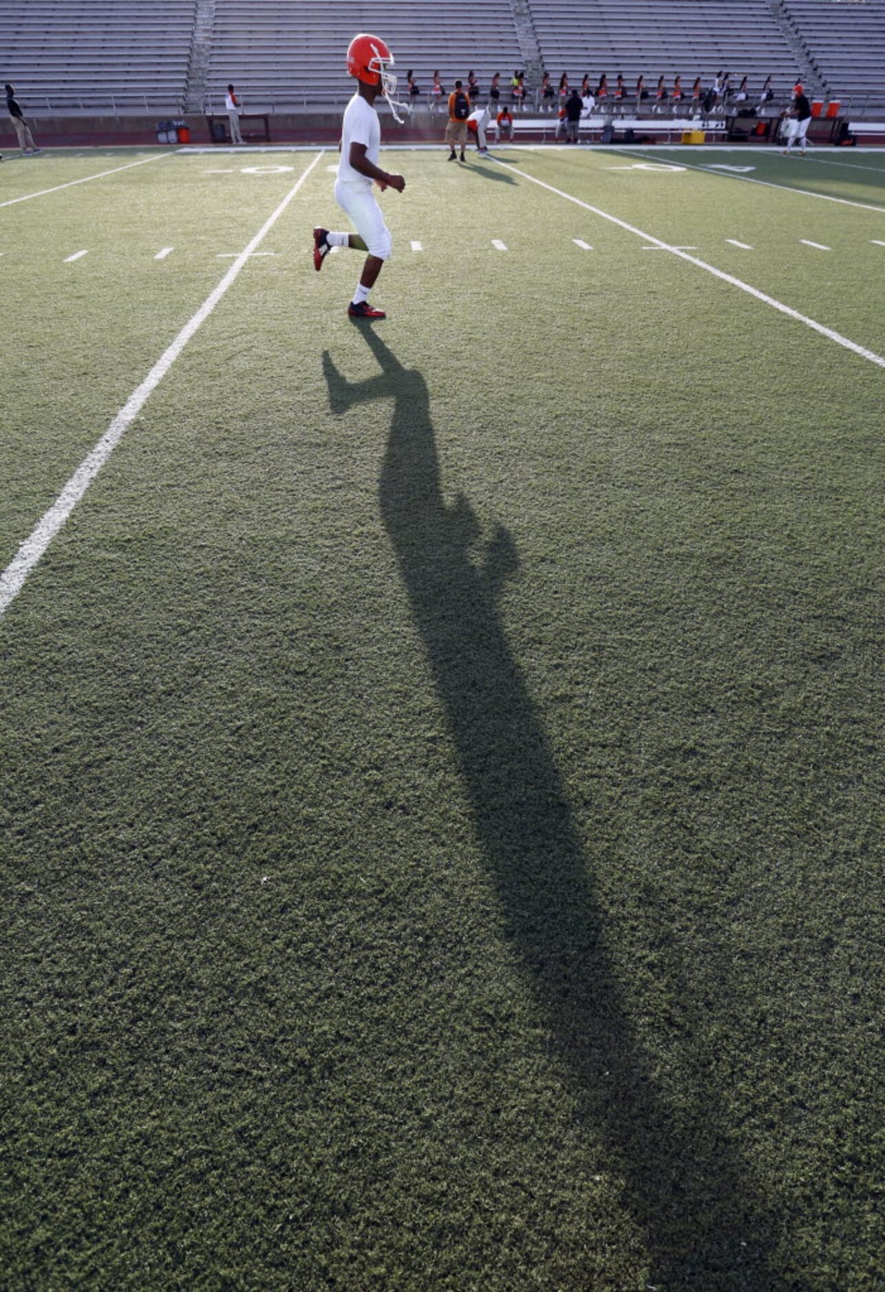 (TXHSFB) A Roosevelt High player and his shadow limber up before the start of a high school...