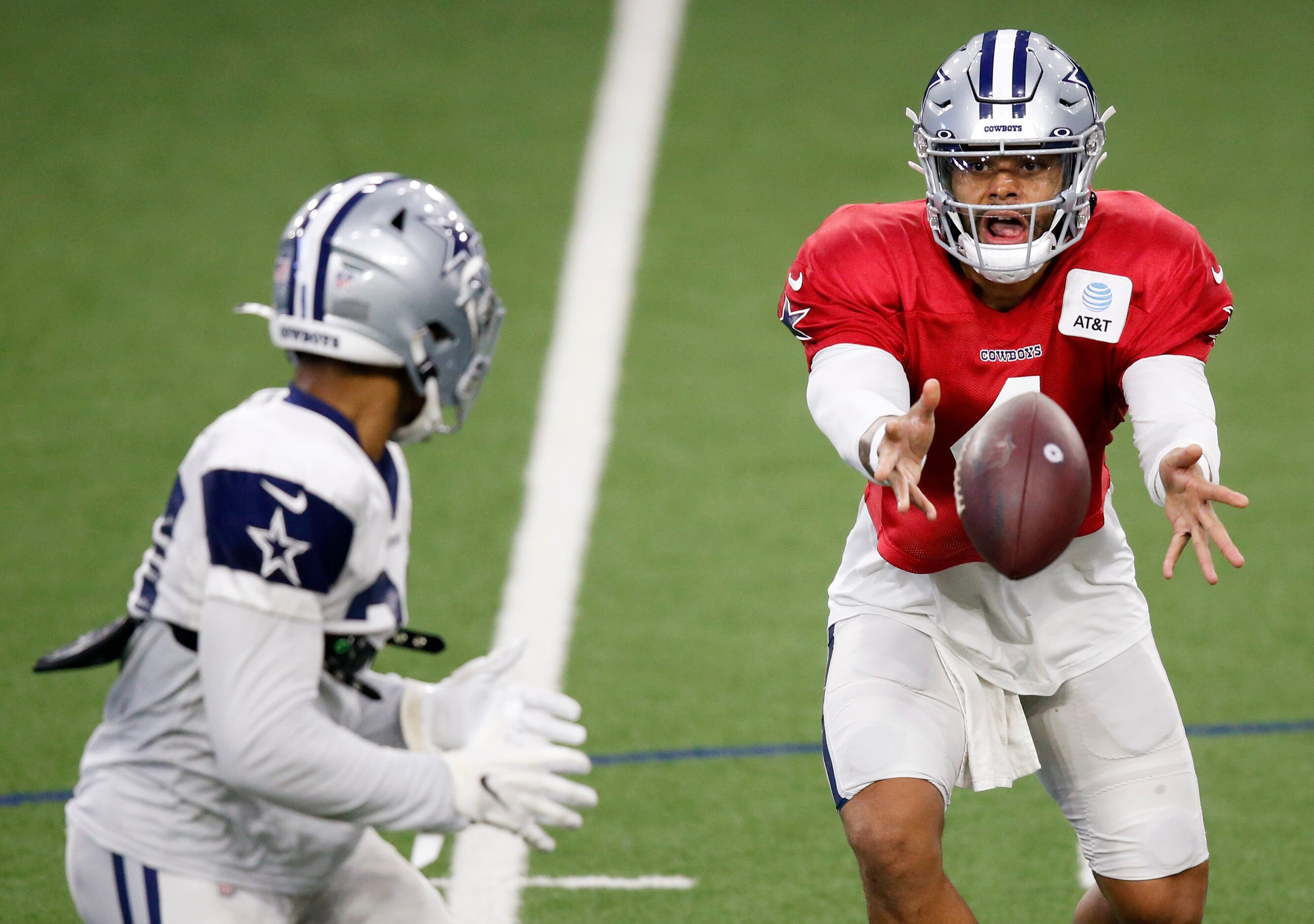 Dallas Cowboys quarterback Dak Prescott (4) tosses the ball to Dallas Cowboys running back...