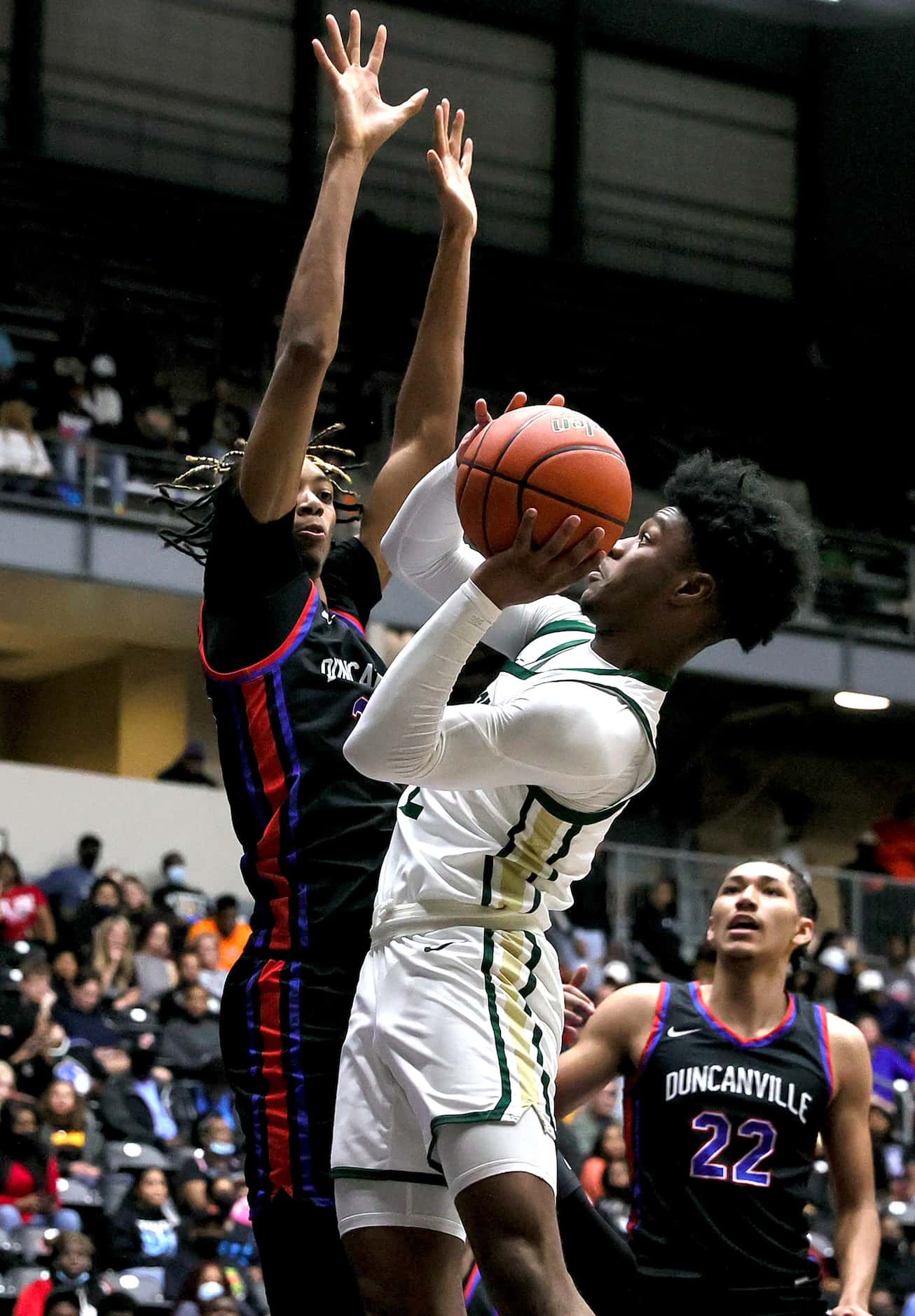 DeSoto guard Evan Phelps (R) tries to get off a difficult shot over Duncanville forward...