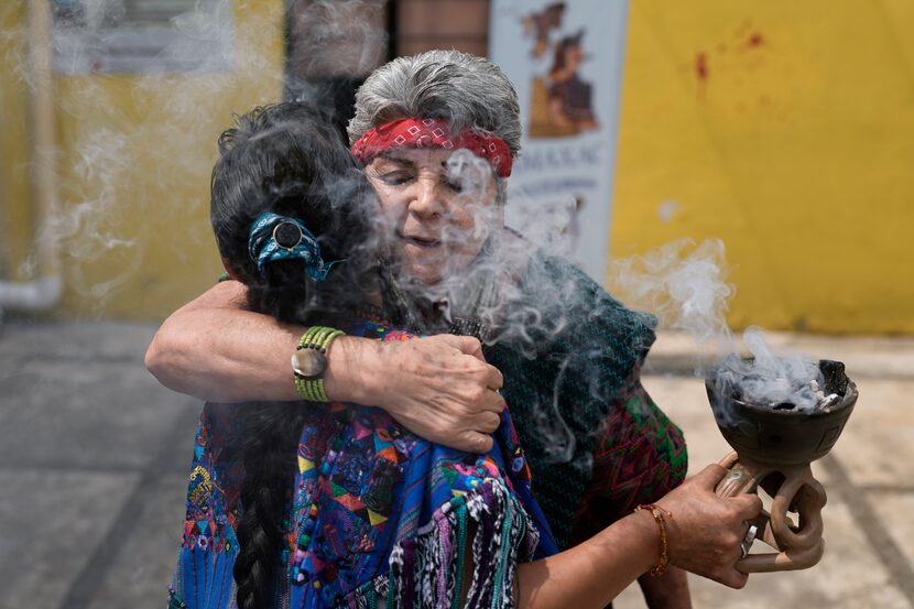 Residentes y miembros de una organización indígena se abrazan durante una ceremonia para...