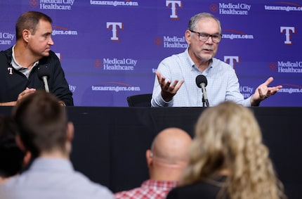 Alongside general manager Chris Young (left), Texas Rangers manager Bruce Bochy responds to...