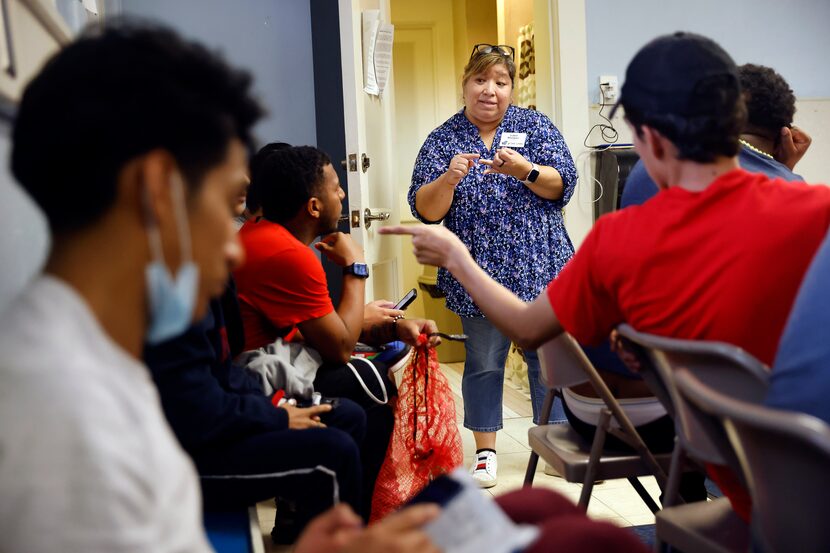 Associate Pastor Isabel Marquez (center) visits with young migrants to arrange their travel...