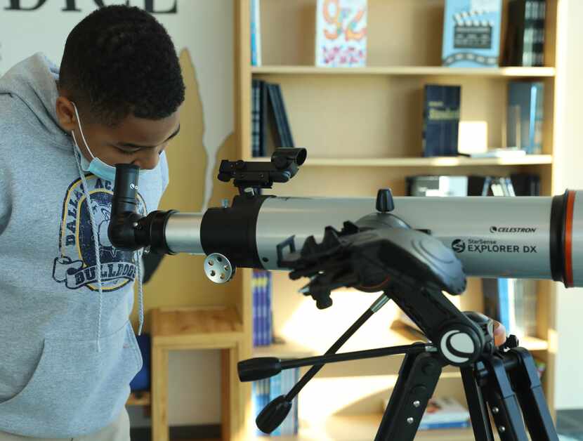 Dallas Academy student Ramadan Hasan looks through a telescope in the school's media center...