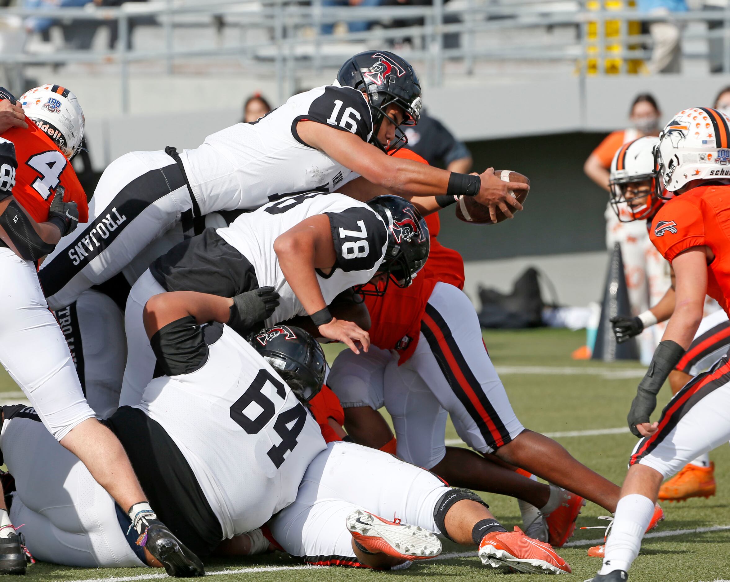 Euless Trinity quarterback Valentino Foni (16) sneaks the ball over Jacob Foni (78) and Save...