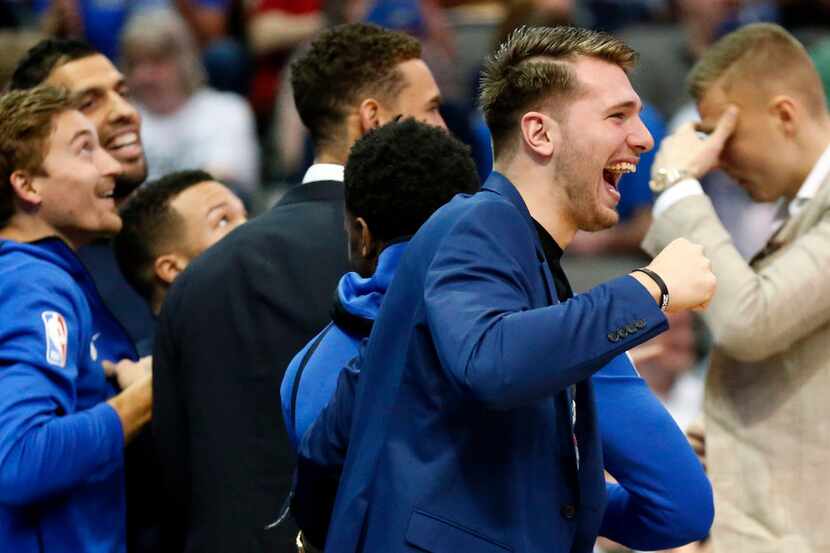 Dallas Mavericks forward Luka Doncic (center) and his teammates react after Dirk Nowitzki...