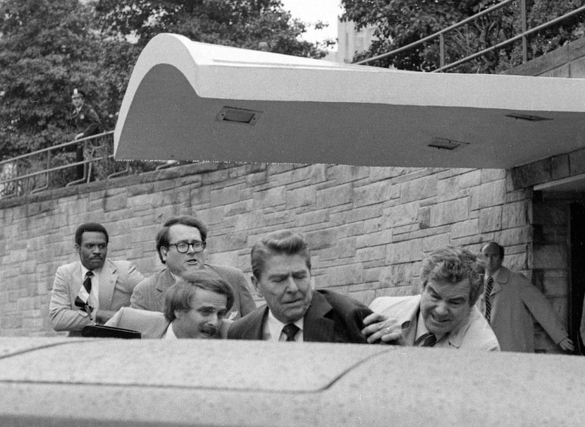 President Ronald Reagan is shoved into the president's limousine by secret service agents...