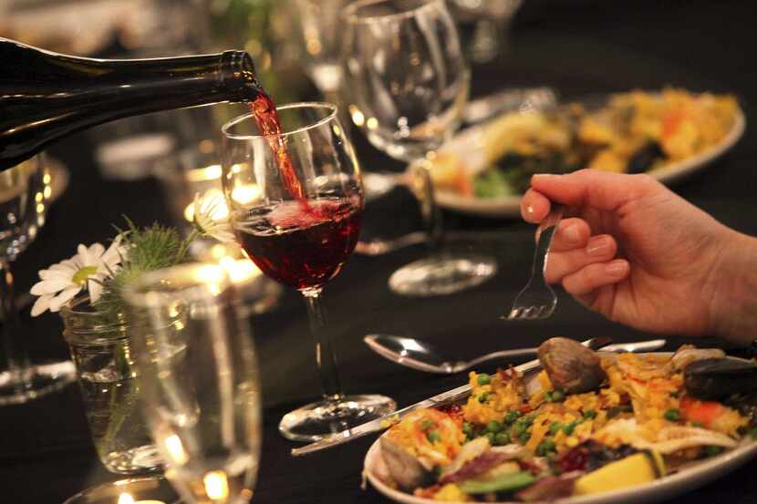 Wine is served as guests dine on Paella made by guest chef/artist Jason Willaford.