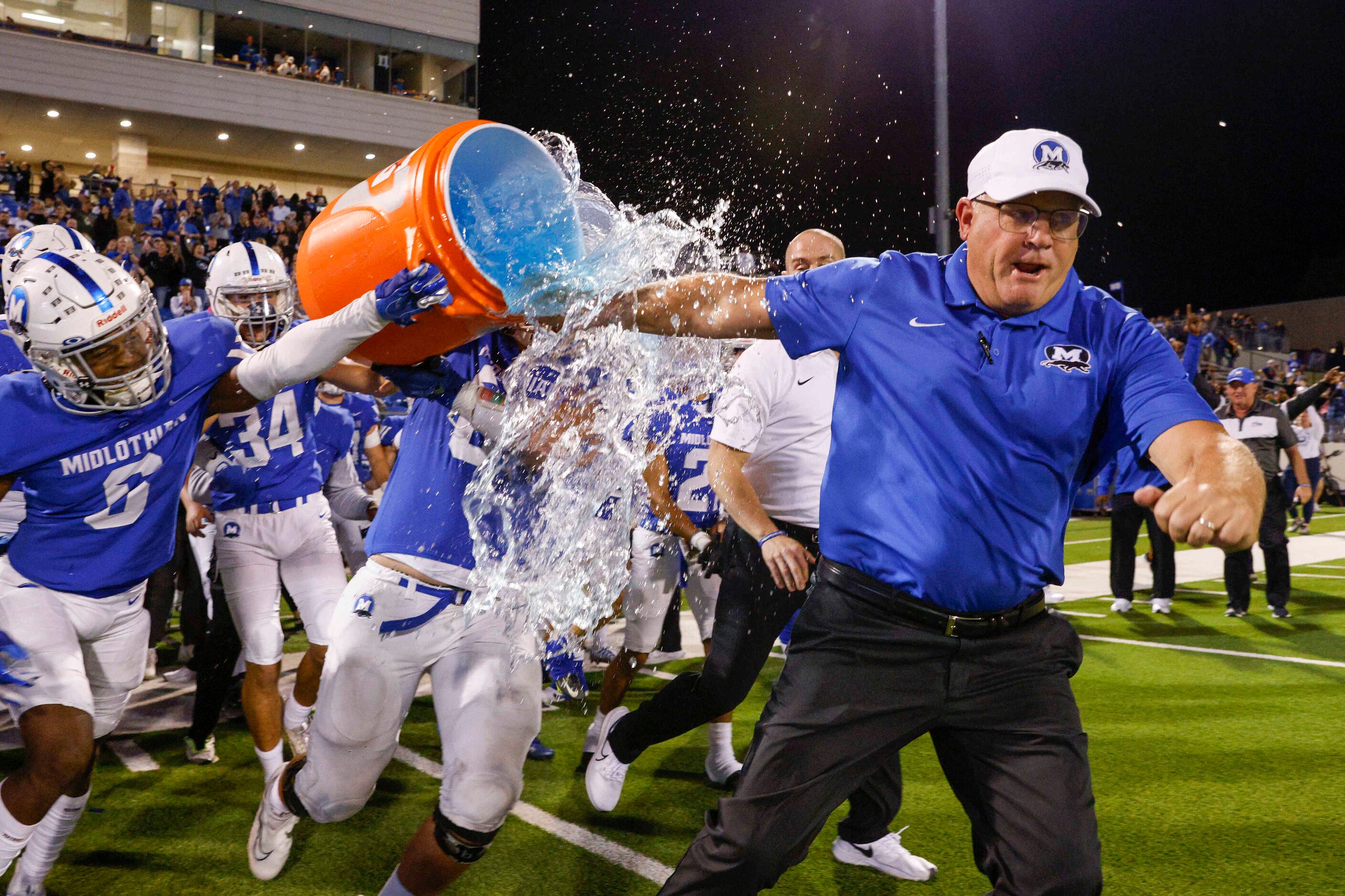 Midlothian head coach Doug Wendel tries to doge a Gatorade bath from defensive back Austin...