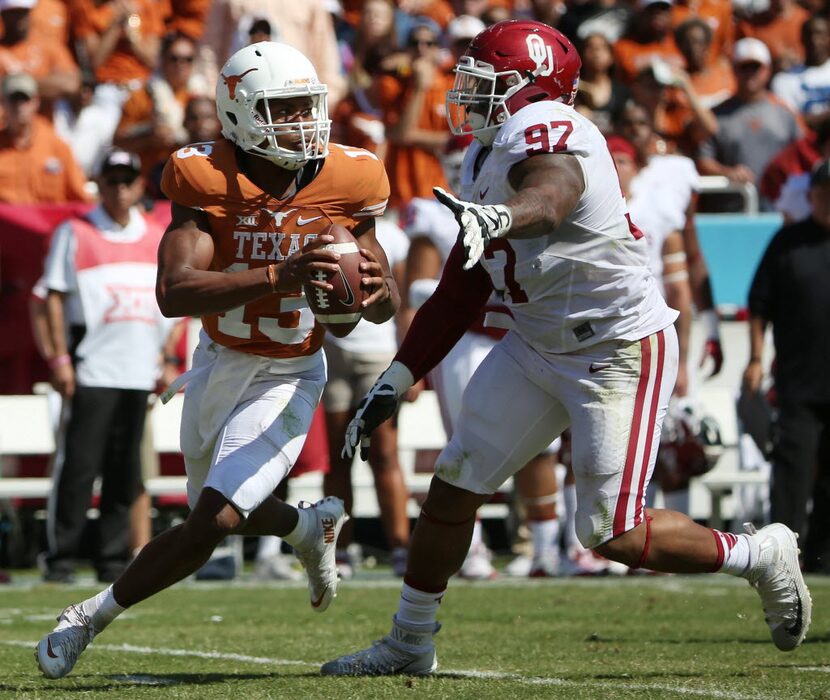 Texas Longhorns quarterback Jerrod Heard (13) avoids a tackle from Oklahoma Sooners...