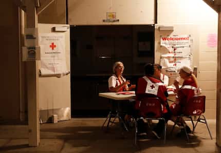 Red Cross volunteers sit at the entrance of an evacuation shelter Friday in Pahoa, Hawaii. 