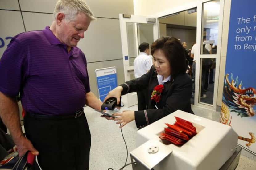  American Airlines ticket agent Jaime Chen (on right) checks in a passenger at Dallas/Fort...