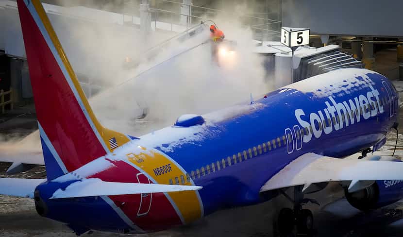 Equipos de trabajo de Southwest Airlines tratando de quitar el hielo y la nieve de una...