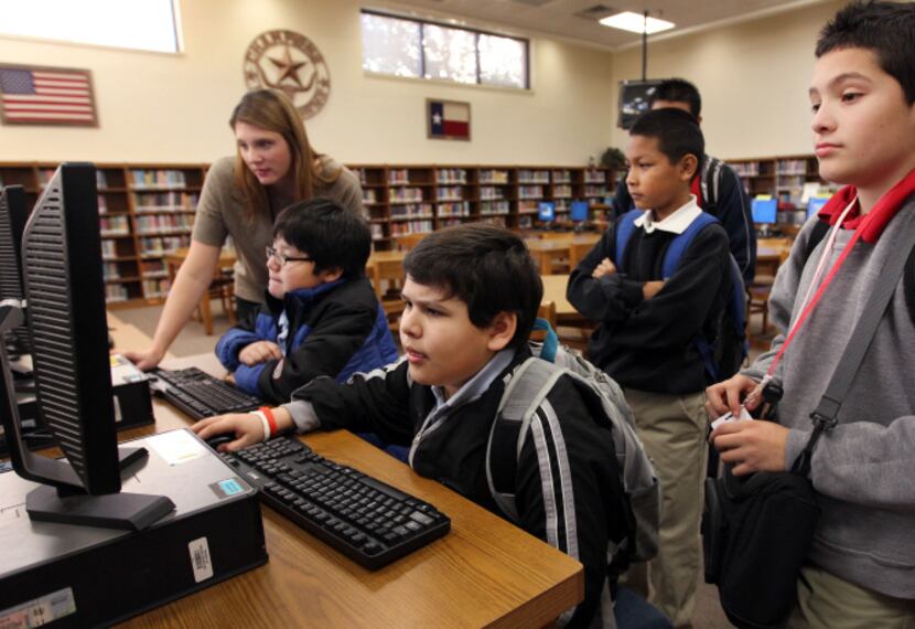 Sixth-grader Osvaldo Martinez (seated) searches through the list of books for Nook e-readers...