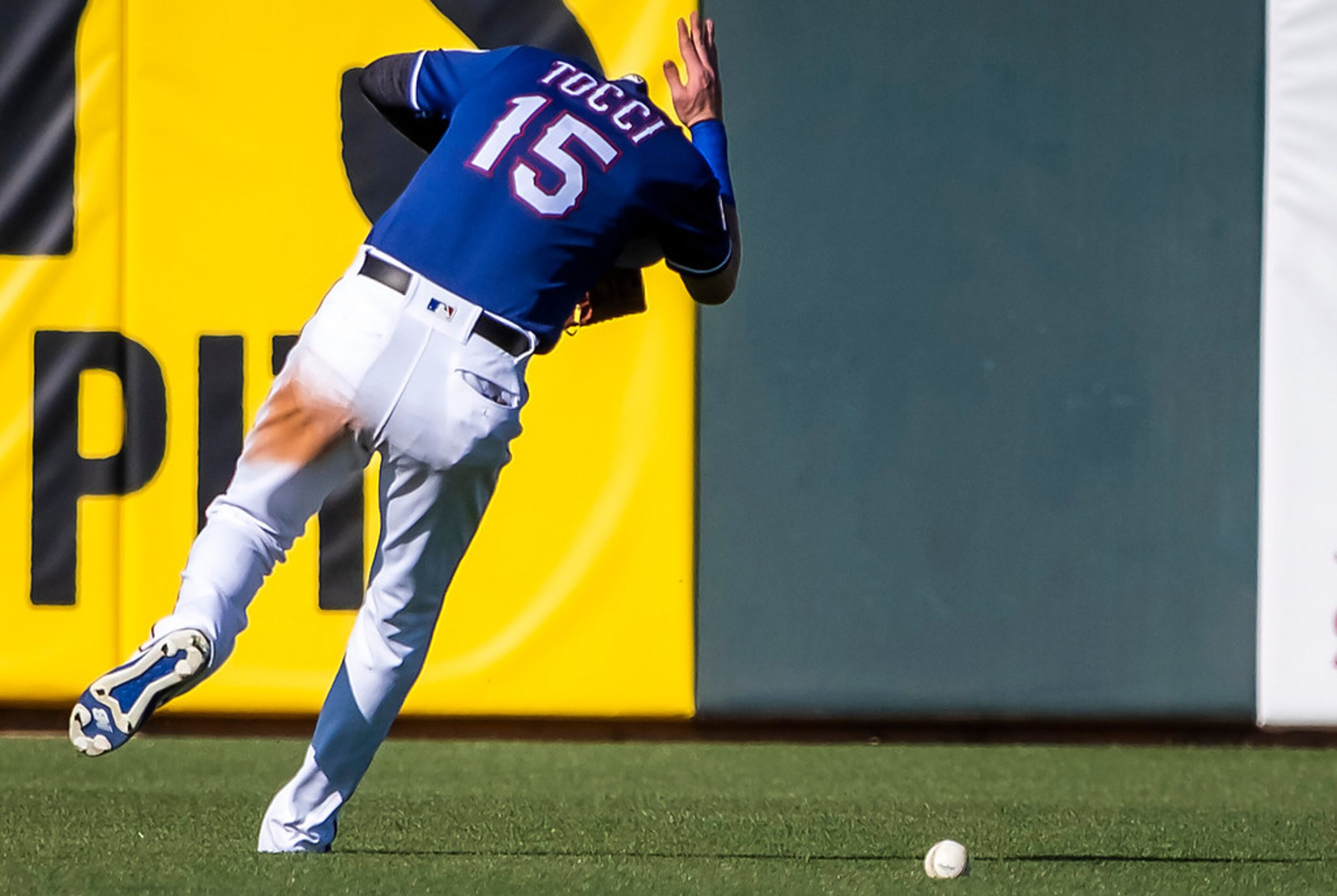 Texas Rangers outfielder Carlos Tocci ducks after losing a ball in the sun for a double by...