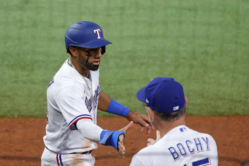 Texas Rangers' Ezequiel Duran, left, is greeted by manager Bruce Bochy, right, after scoring...