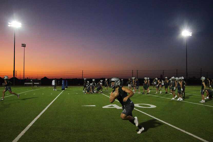 Sam Noskin, 16, runs after the catch as the sun begins to rise during football practice at...