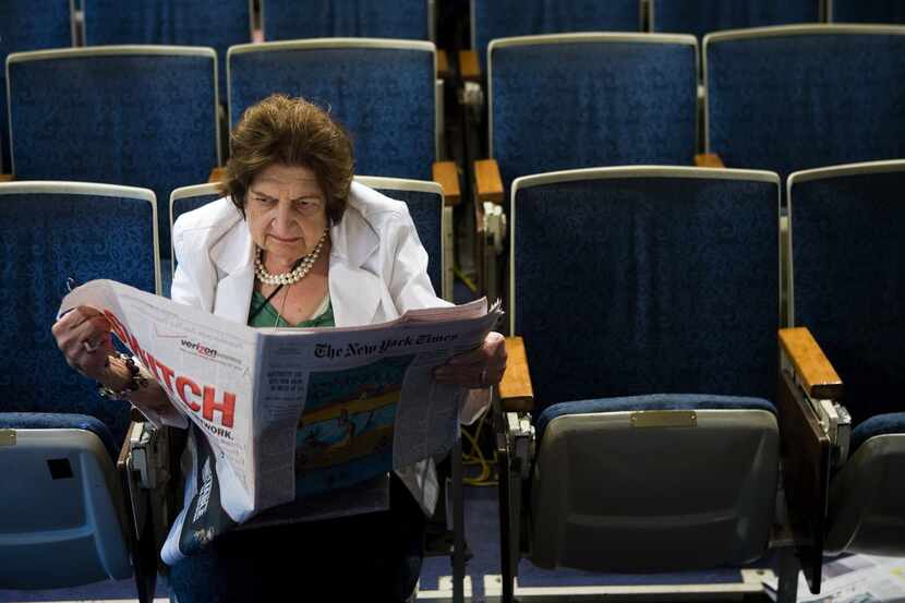 Senior White House Correspondent Helen Thomas reads the newspaper while sitting in her chair...