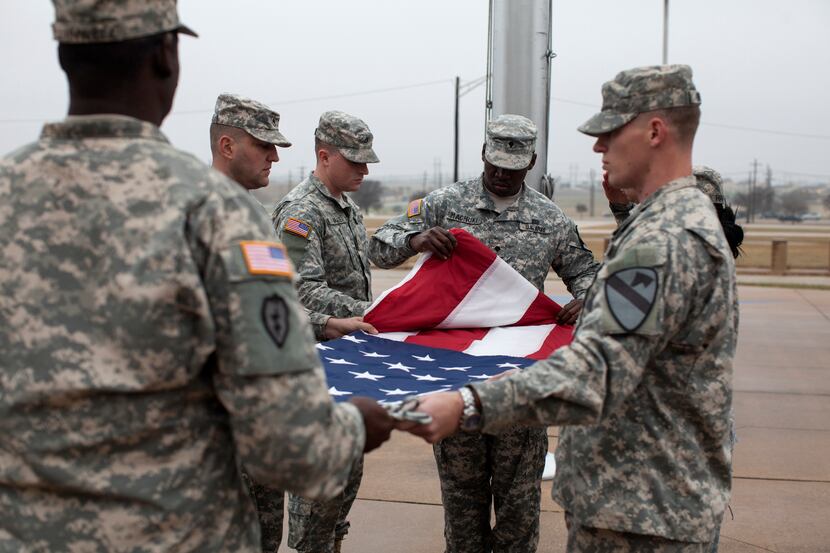 Soldiers fold a lowered flag at Fort Hood on Dec. 30 to mark the official end of the war in...
