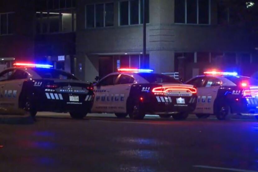 Dallas police squad cars line up near where a man was shot after he repeatedly fired his gun...