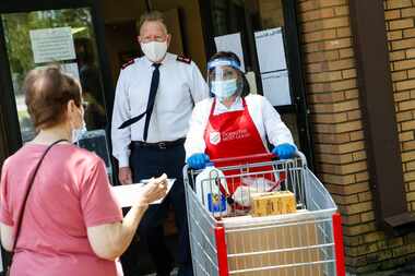 Salvation Army Major Todd Hawks, back, assists employee Maria Rincon, center, with a food...