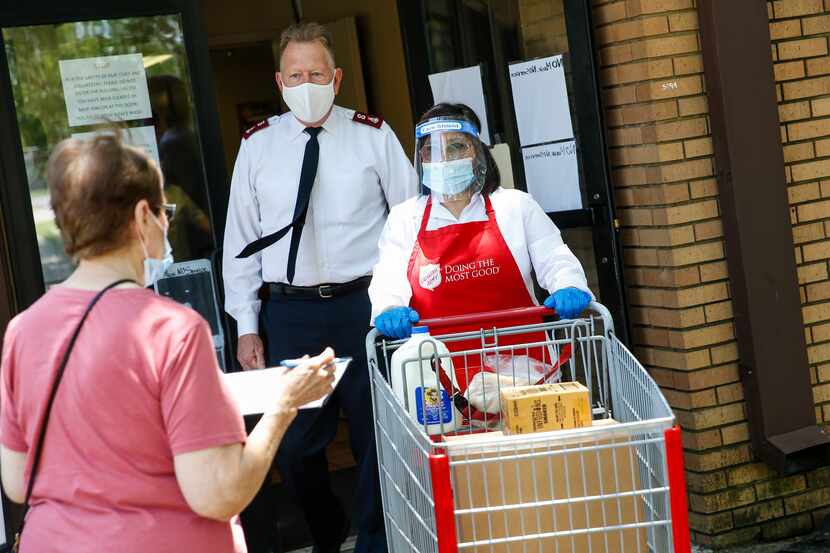 Salvation Army Major Todd Hawks, back, assists employee Maria Rincon, center, with a food...