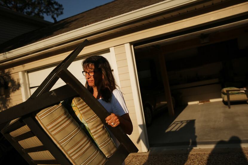 Homeowner Nancy Radecki, whose home was spared from flooding, puts out lawn furniture for...