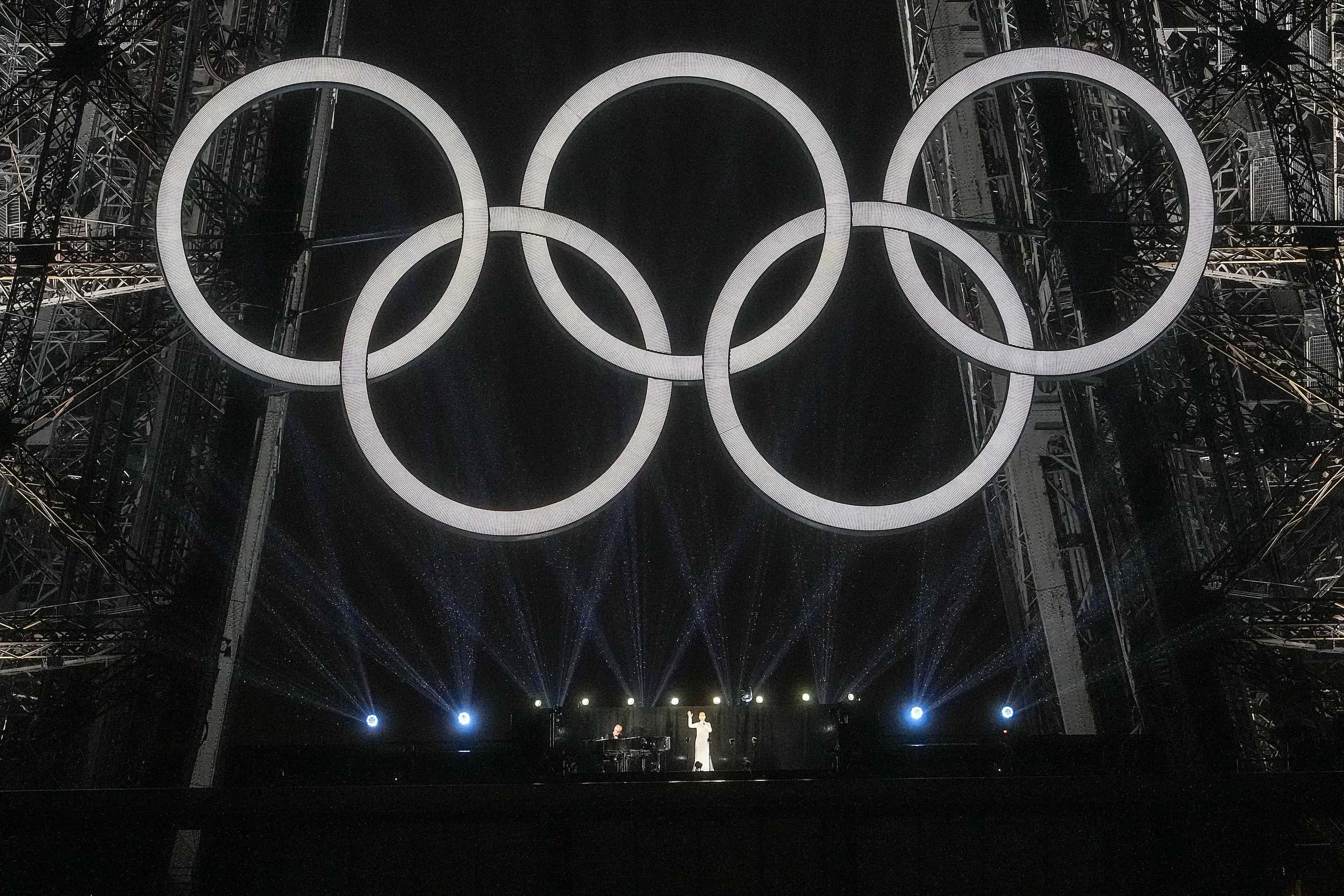 Singer Celine Dion performs beneath the Olympic Rings on the Eiffel Tower during opening...