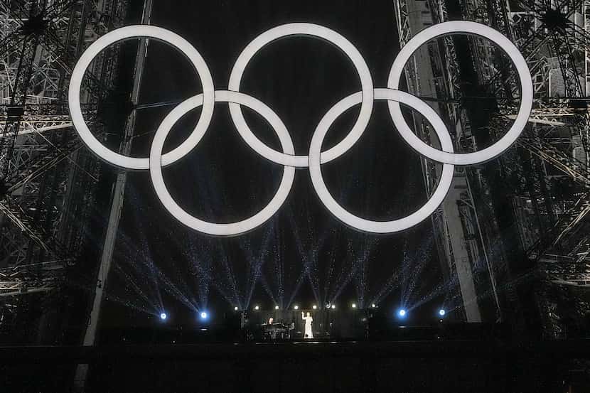 Singer Celine Dion performs beneath the Olympic Rings on the Eiffel Tower during opening...