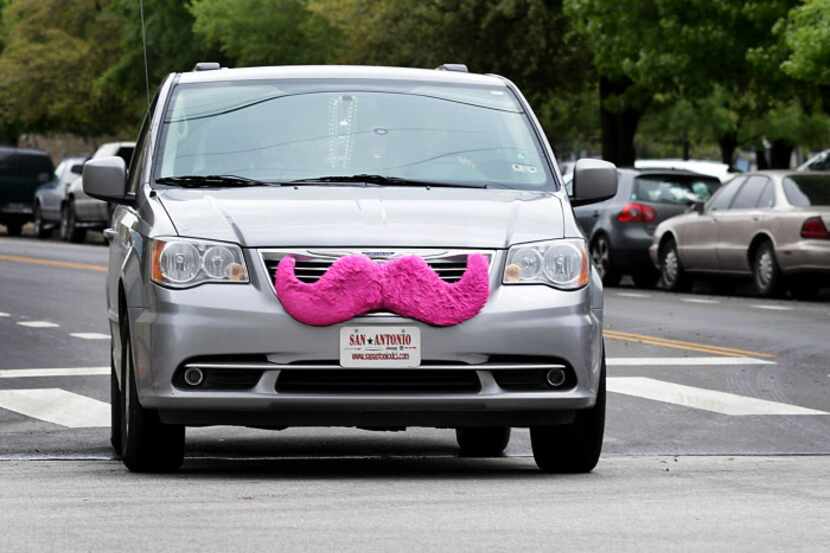 A Lyft car makes its way on a San Antonio street with the signature pink mustache.