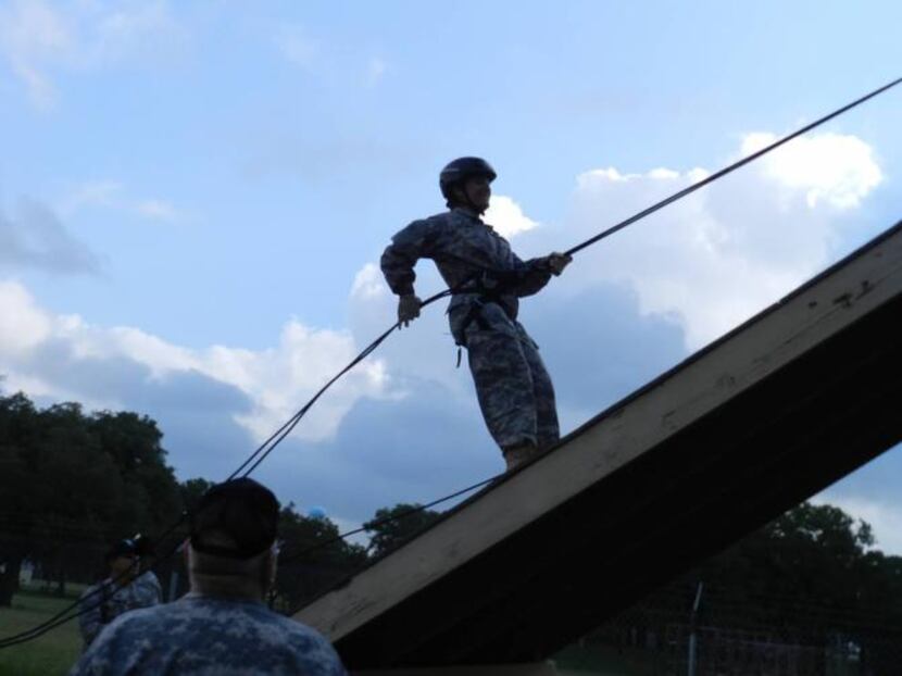 
A Dallas ISD JROTC cadet uses a rope to climb an obstacle at Camp Bullis during the...