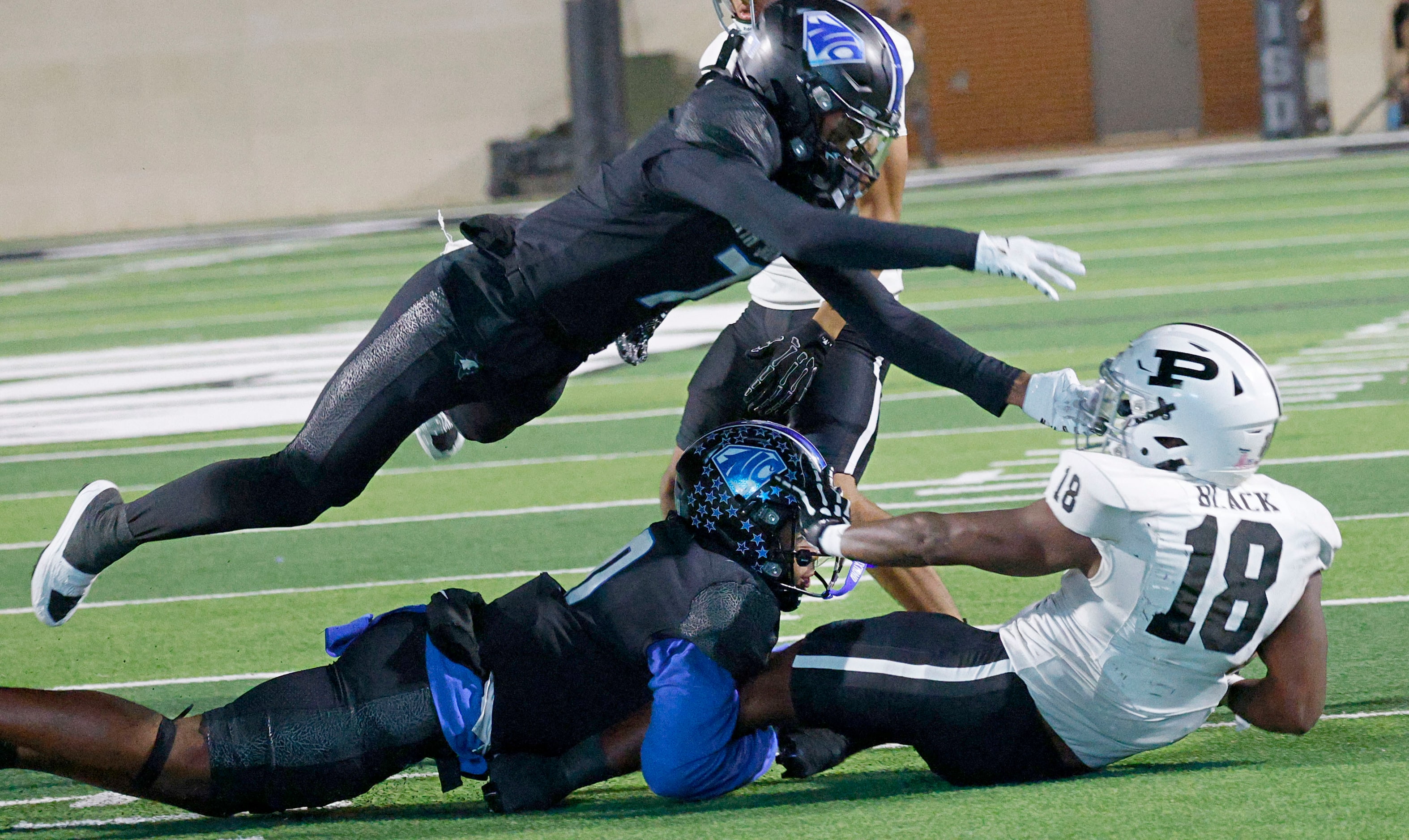 Permian's Gavin Black (18) is tackled by North Crowley's Ja'Brelle Asberry (0), bottom, and...