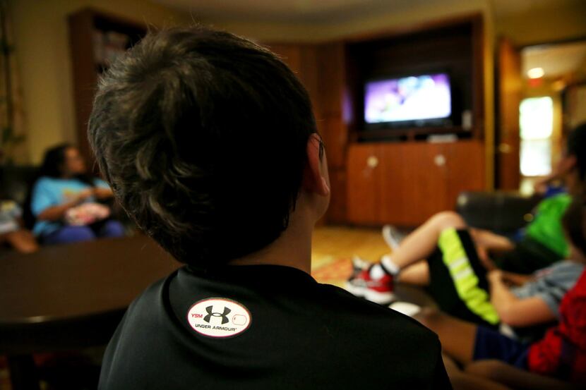 A boy watches TV at Jonathan's Place, which serves abused and neglected children, in Garland...