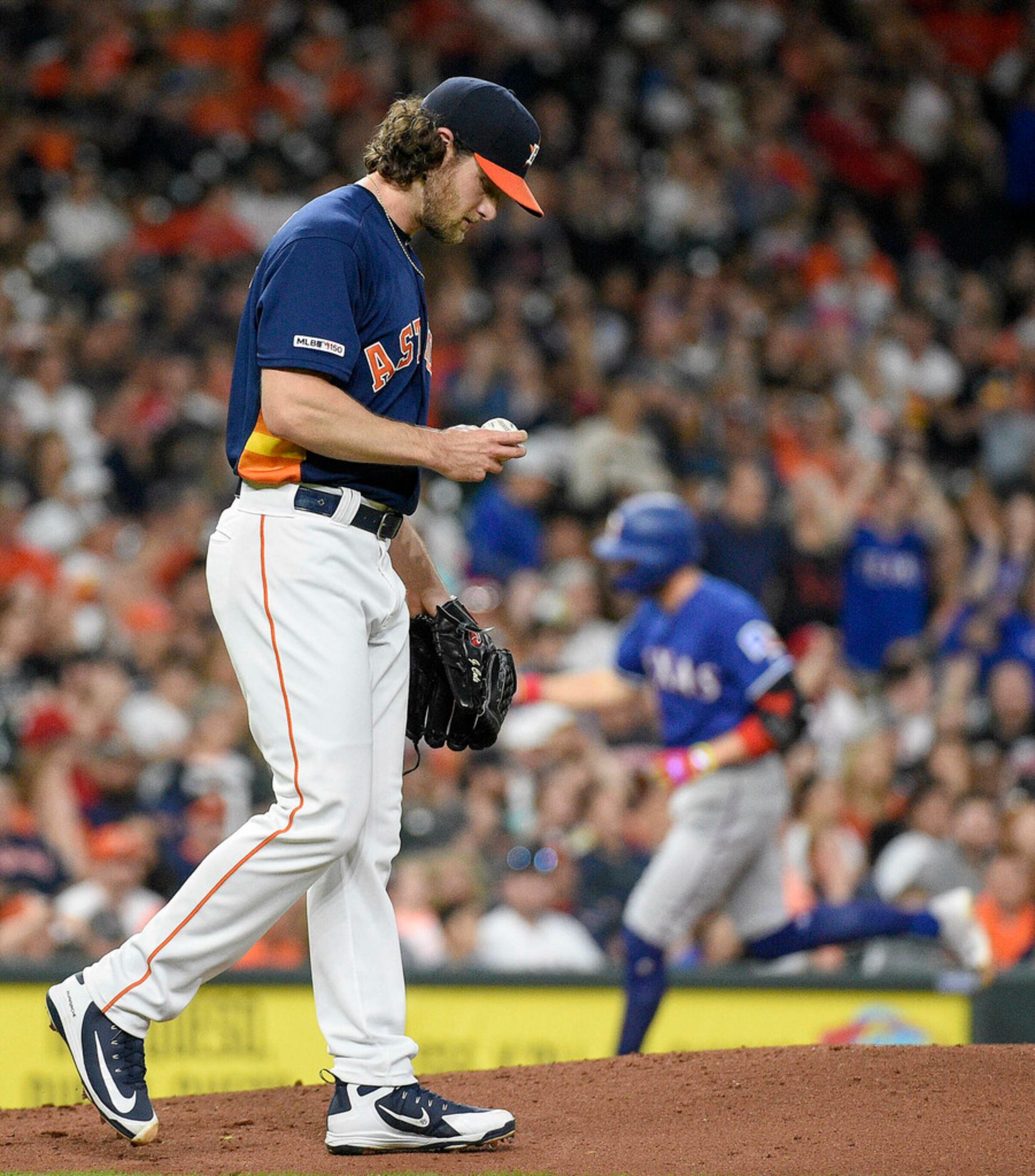 Houston Astros starting pitcher Gerrit Cole, left, walks back to the mound as Texas Rangers'...