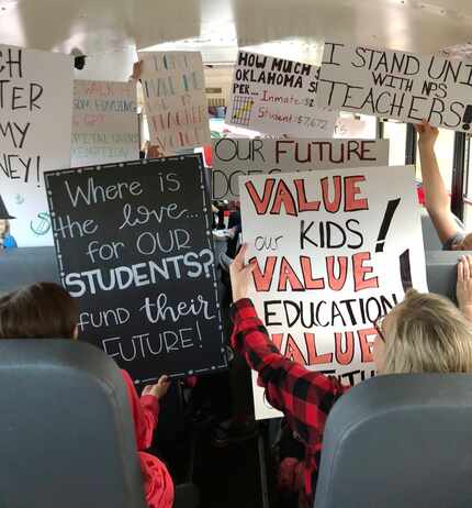 Teachers hold up their signs on a school bus as the head to the Oklahoma capitol in Oklahoma...