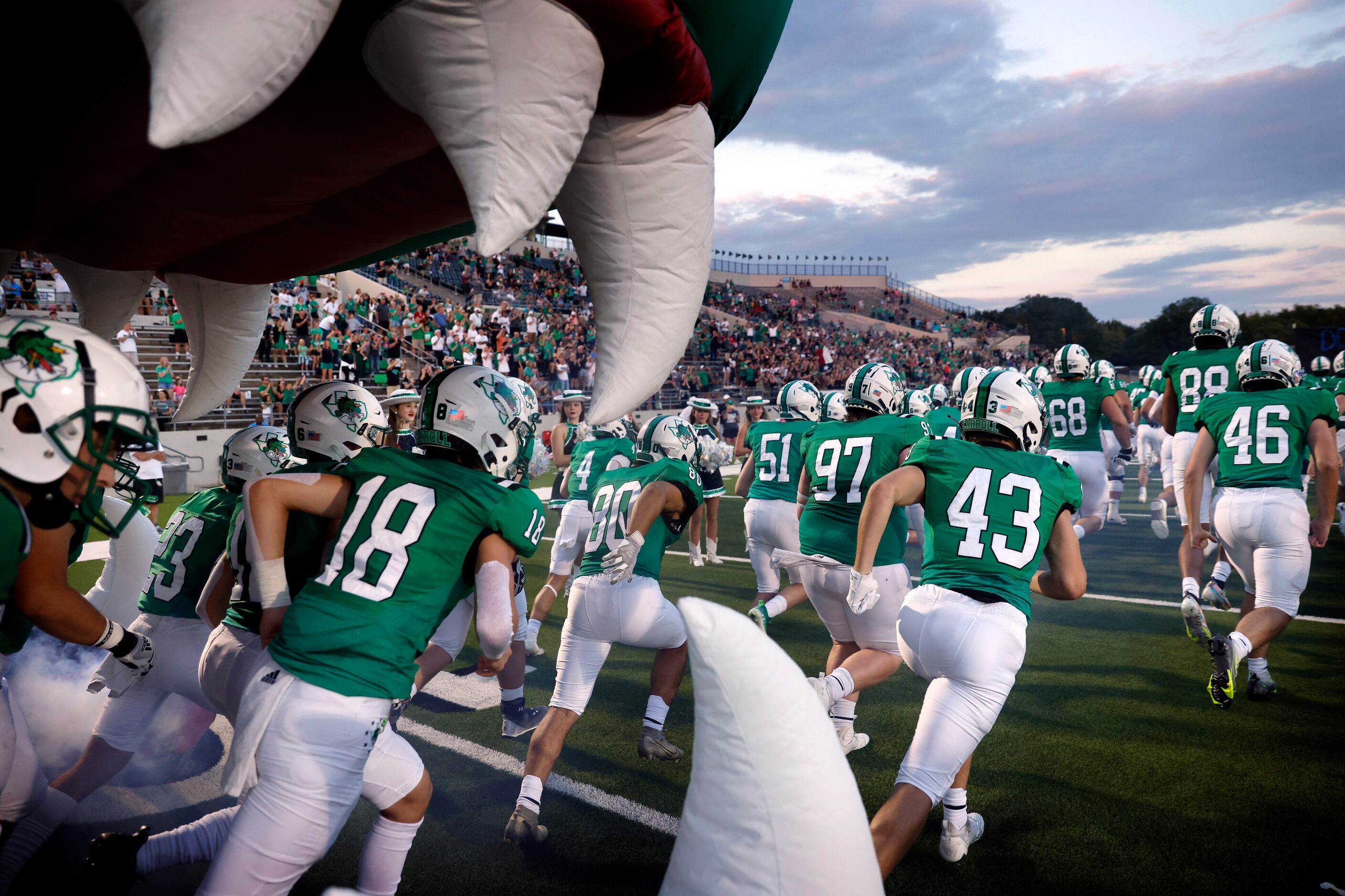 The Southlake Carroll football team races out of a Dragon mascot inflatable before the...