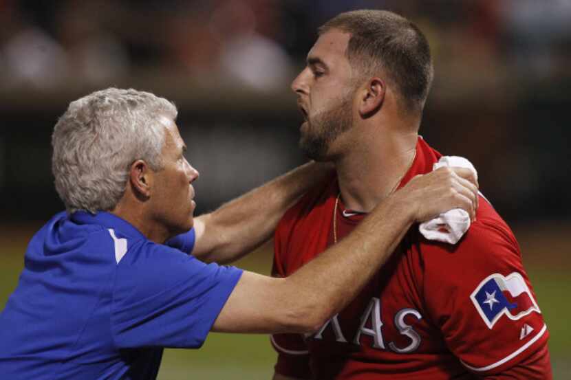 Texas Rangers catcher Mike Napoli (25) is checked over by Rangers Trainer Jamie Reed after...
