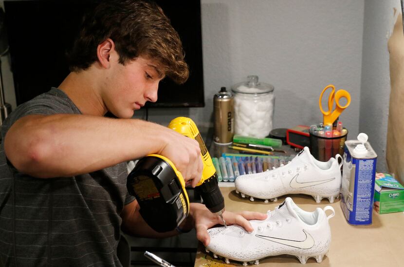 Luke Savage, 16, drills holes in cleats he's creating for SportsDayHS in his home in Dallas...
