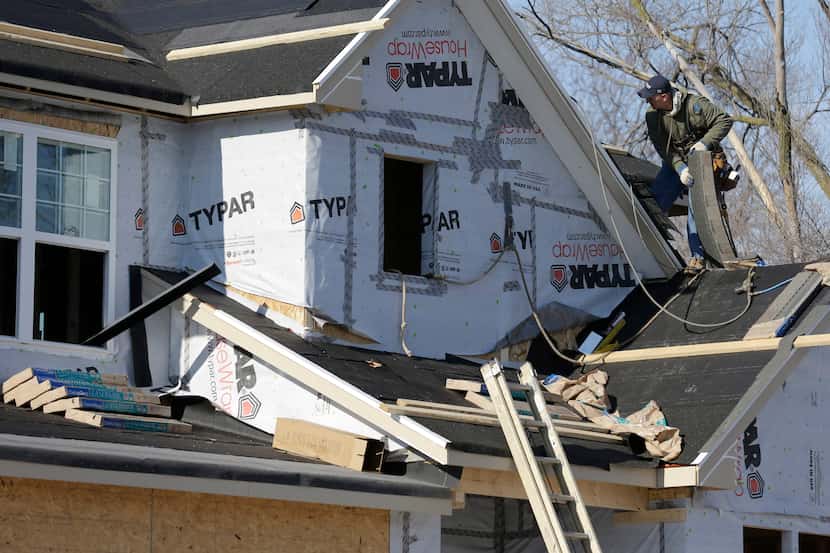 FILE - In this Dec. 27, 2013 file photo, a builder works on the the roof of a new home under...