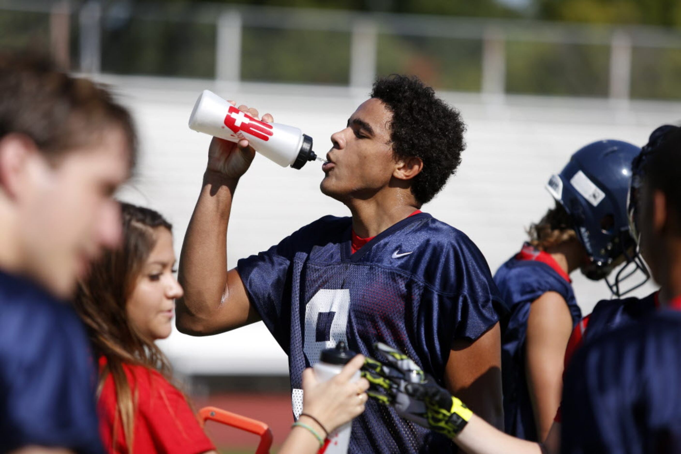 Wide receiver Jalen Guyton grabs a drink during the first day of football practice for...
