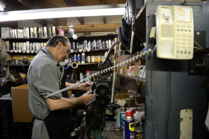 
Kenneth Burks repairs a shoe and answers a phone call in the back room of his shop, Messina...