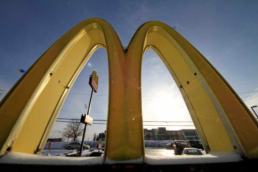 In this Tuesday, Jan. 21, 2014, photo, cars drive past the McDonald's Golden Arches logo at...
