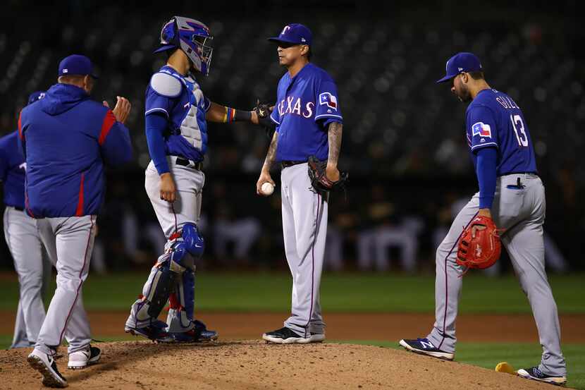 Texas Rangers pitcher Jesse Chavez, center, waits to be removed by manager Jeff Banister,...
