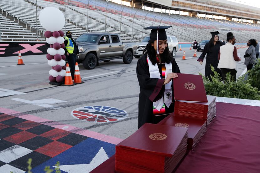 Michelle Castro picks up her diploma cover at the finish line as Texas Woman’s University...