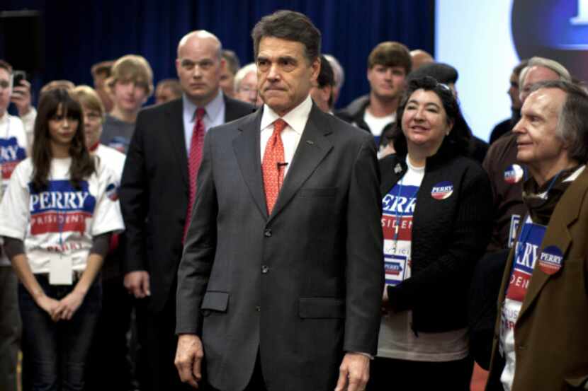 Workers clean up after Republican presidential candidate Rick Perry spoke at his caucus...
