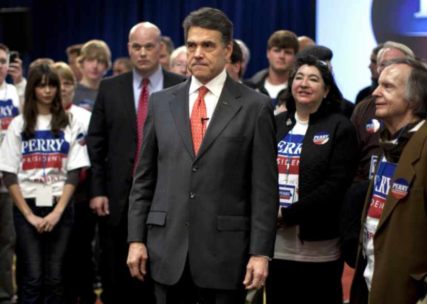 Workers clean up after Republican presidential candidate Rick Perry spoke at his caucus...