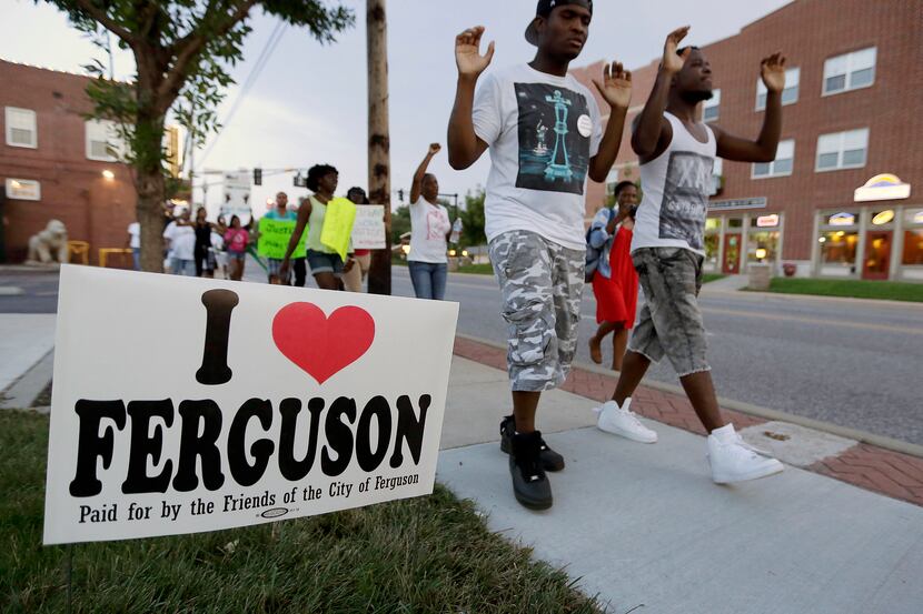 In this Aug. 20, 2014 file photo, people march to protest the shooting of Michael Brown in...