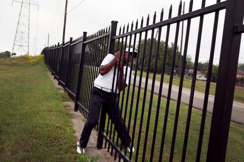 Lester Bell struggles as he squeezes through the same fence he used to slide through with...