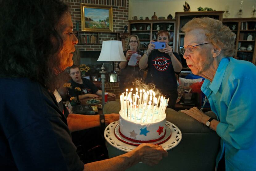 Lois Kreger blew out the candles on her cake held by Sunny Yeatts during her 100 year...